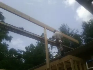 Carpenter setting a ridge beam over a new addition frame — Ice Dam Removal by Roofing Brothers in Evergreen