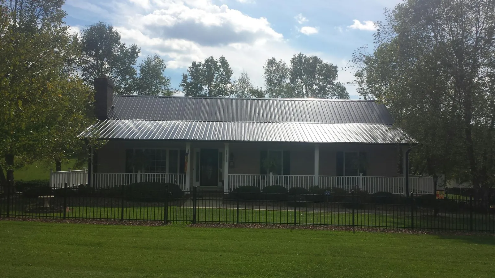 Gray metal roof on a brick ranch with a full width front porch — Gutter Guard Installation work by our crew in Evergreen